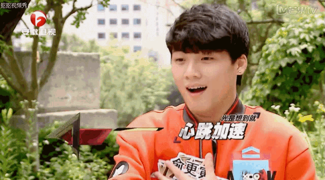 a young man in an orange jacket with chinese writing on the front
