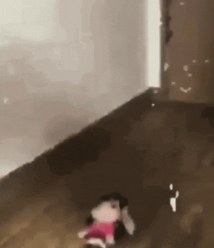 a stuffed animal is sitting on a wooden floor next to a door .