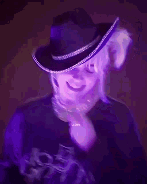 a blurry picture of a person wearing a purple shirt and hat .
