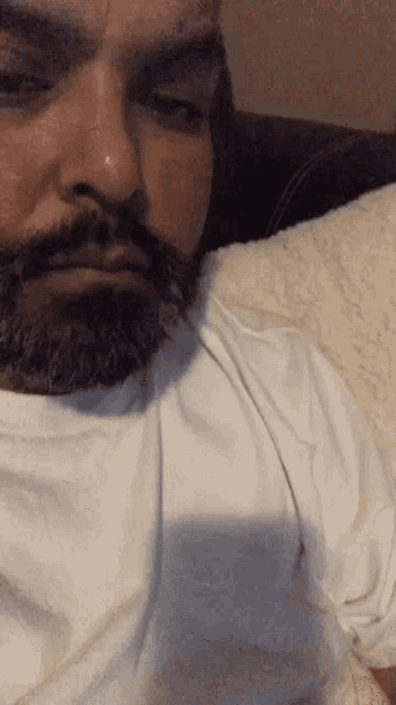 a man with a beard is wearing a white shirt and a nose ring