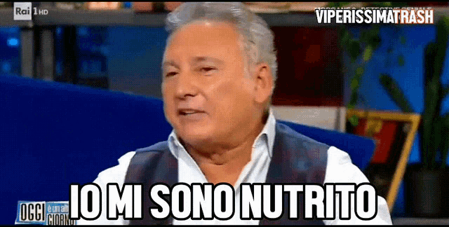 a man is sitting in front of a screen that says " io mi sono nutrito " on it