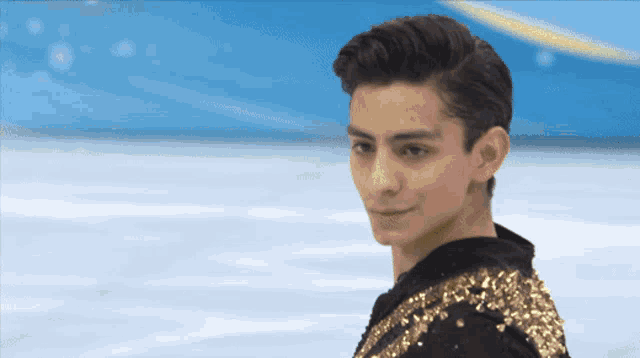 a young man wearing a black and gold outfit stands on a ice rink