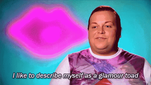 a man is sitting in front of a pink heart and saying `` i like to describe myself as a glamour toad ''