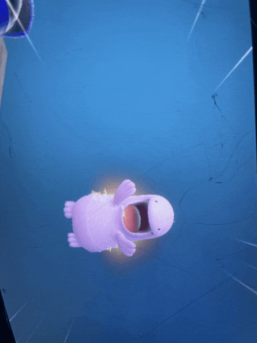 a purple stuffed animal with its mouth open on a blue surface