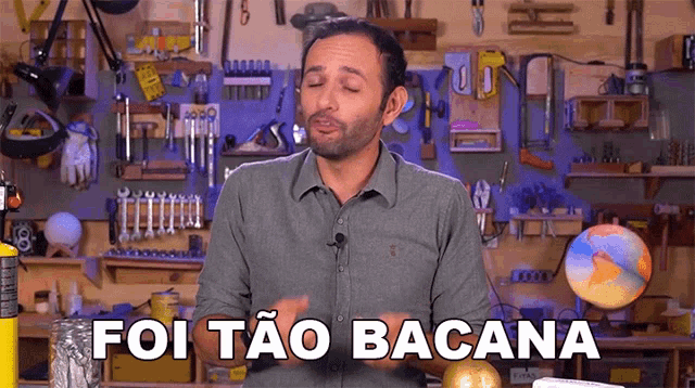 a man in a grey shirt is standing in front of a workbench and says foi tao bacana