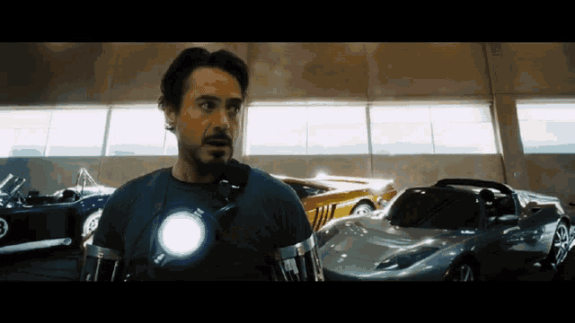 a man in an iron man suit is standing in front of a row of cars