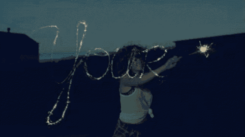a woman is holding a sparkler and writing the word jours in the dark