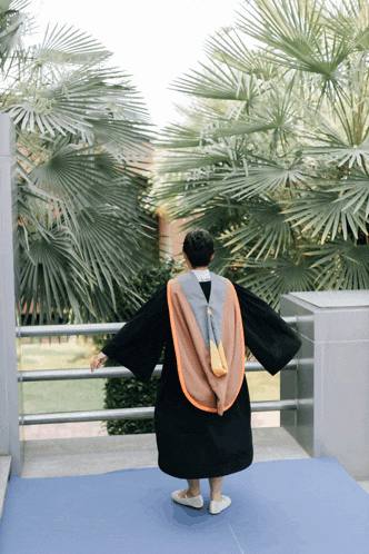 a man in a graduation gown stands on a blue mat