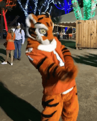a mascot in a tiger costume stands in front of a group of people