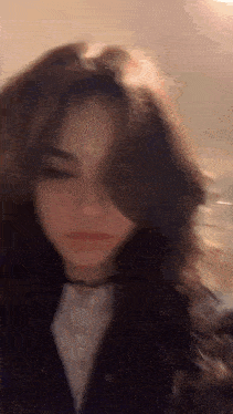 a close up of a woman 's face with her eyes closed and her hair blowing in the wind .