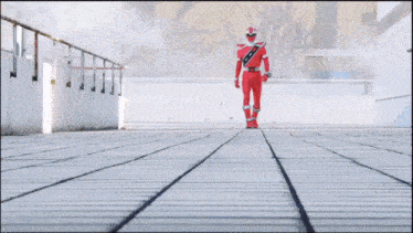 a man in a red superhero costume is walking down a walkway .