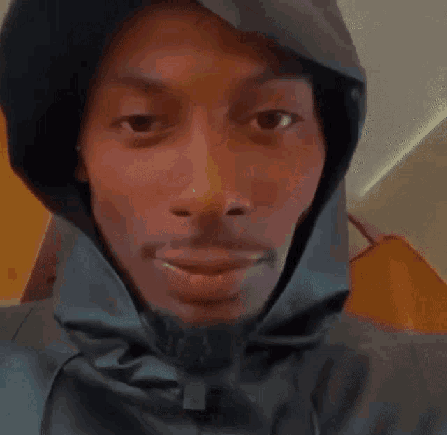 a man with a hood on his head is smiling .