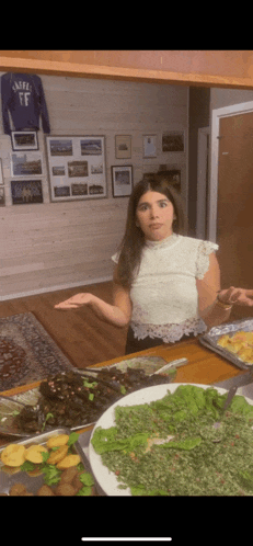 a woman sitting at a table with plates of food and a shirt that says ff on the wall behind her