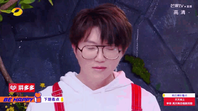 a man wearing glasses and red overalls has a be happy sign on his shirt