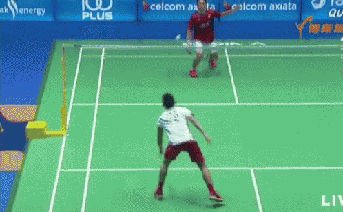 two men are playing badminton on a court with advertisements for celcom axiata