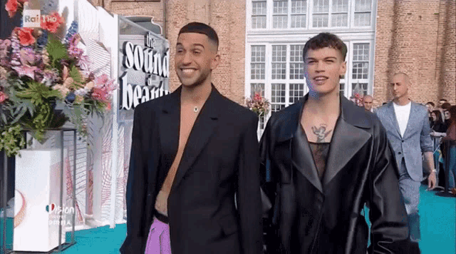 two men walking on a blue carpet in front of a sign that says the sound heart