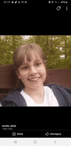 a girl wearing glasses is smiling for a picture