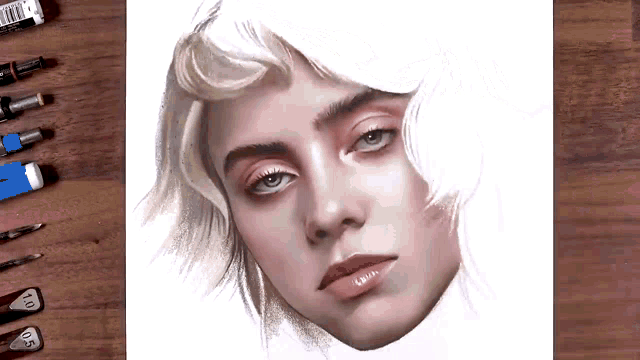 a drawing of billie eilish 's face is on a wooden table surrounded by pencils .