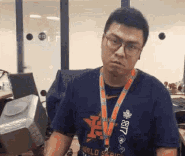 a man wearing glasses and a lanyard is holding a hammer in his hands .
