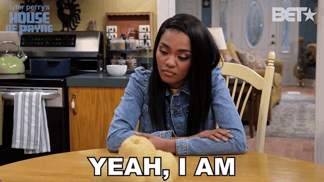 a woman sits at a table with a pumpkin and says " yeah , i am "