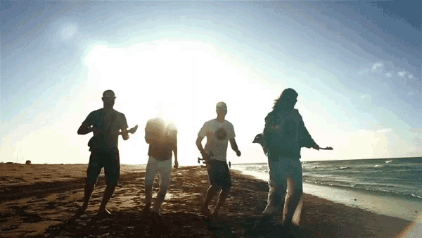 a group of people walking on a beach with one wearing a t-shirt that says ' hawaii '