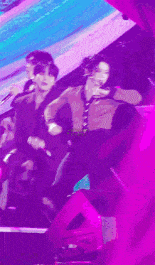 a group of people are dancing on a stage with a purple background
