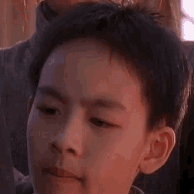 a close up of a young boy 's face with a woman behind him