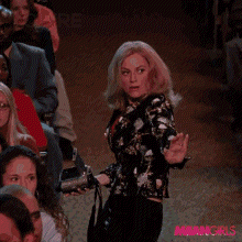 a woman is dancing in front of a crowd with the words " you 're doing " behind her