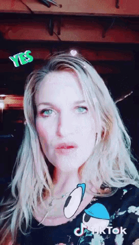 a woman wearing a black shirt with donald duck on it has a tiktok sticker on her face