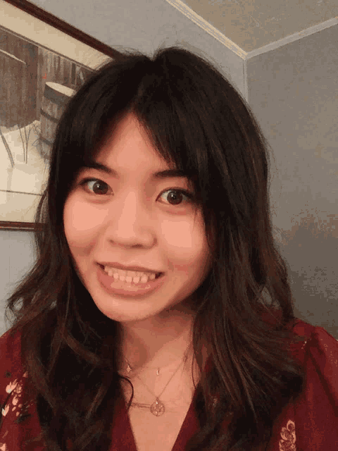 a woman in a red shirt is smiling in front of a picture