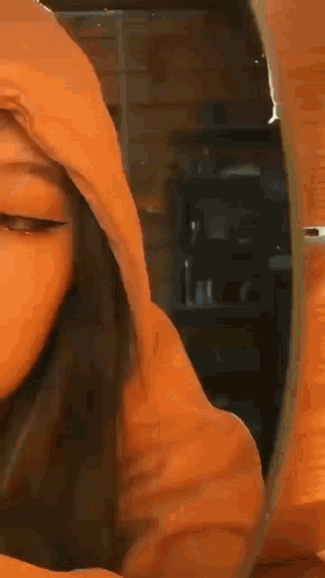 a close up of a girl wearing a hoodie with her hand on her face .