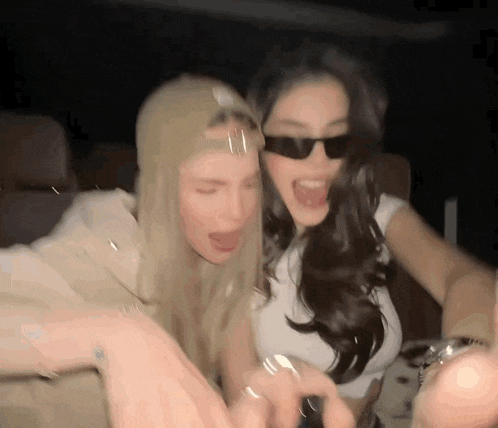 two women wearing sunglasses are standing next to each other .
