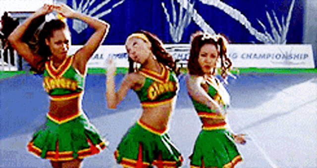 three cheerleaders are dancing in front of a sign which says championship