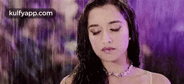 a woman is standing in the rain with her eyes closed and her hair is wet .