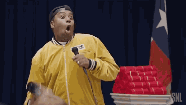 a man in a yellow jacket is holding a microphone in front of a podium with red towels .