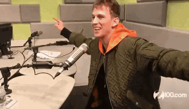 a young man in a green jacket is sitting in front of a microphone in a radio station .