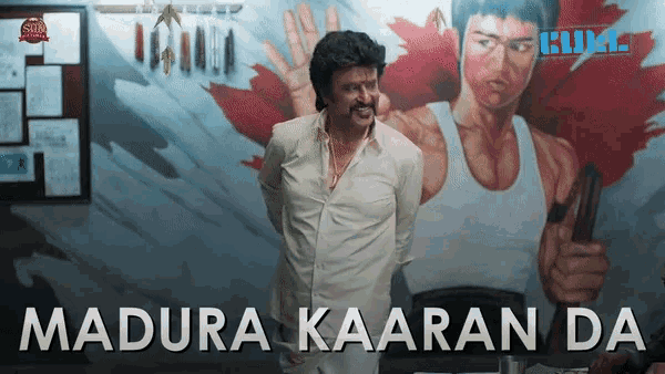 a man in front of a mural with the words madura kaaran da
