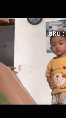 a little boy wearing a yellow shirt with a bear face on it