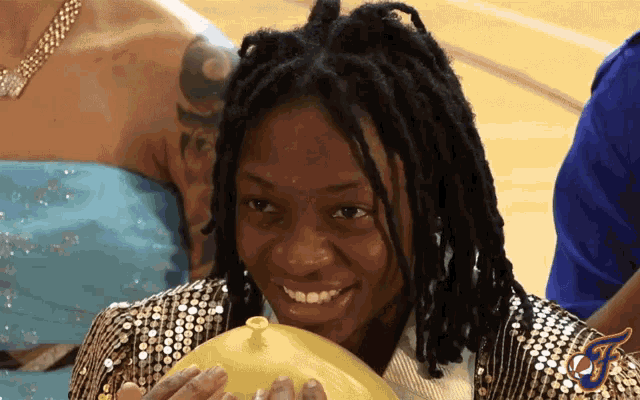 a woman with dreadlocks is holding a yellow balloon