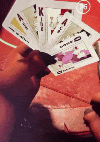 a person is holding a playing card with the number 26 in the corner