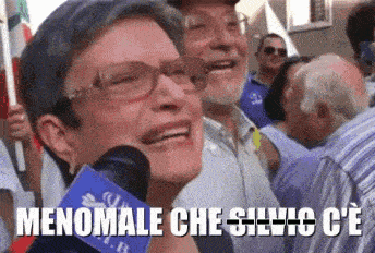 a woman wearing glasses is smiling while holding a microphone with the words menomale che silvio c'e on it