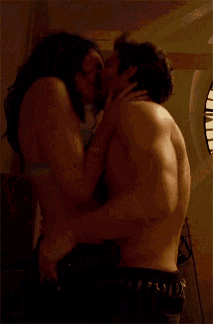 a man without a shirt is holding a woman in his arms