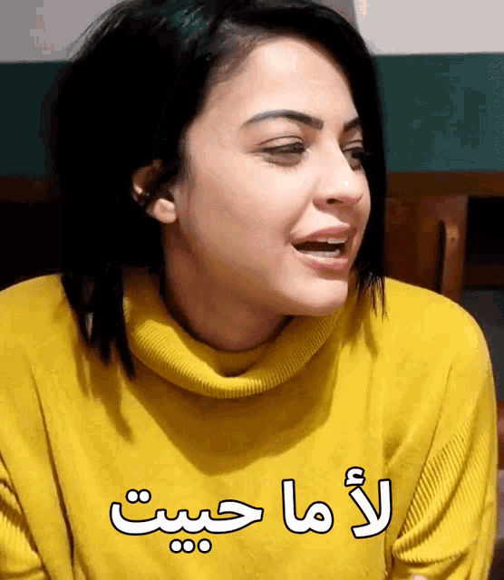 a woman wearing a yellow sweater with arabic writing on the front