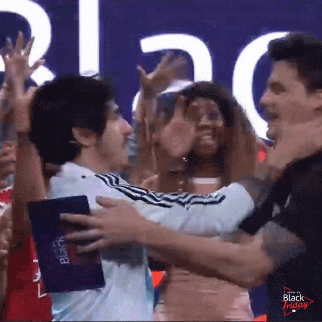 a man is hugging another man in front of a black friday sign