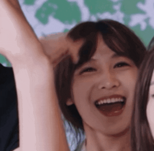 a close up of a woman 's face with her mouth open and her hands in the air .