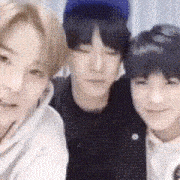 a group of three young men are standing next to each other and looking at the camera .
