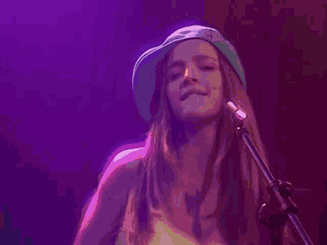 a woman singing into a microphone with a hat on