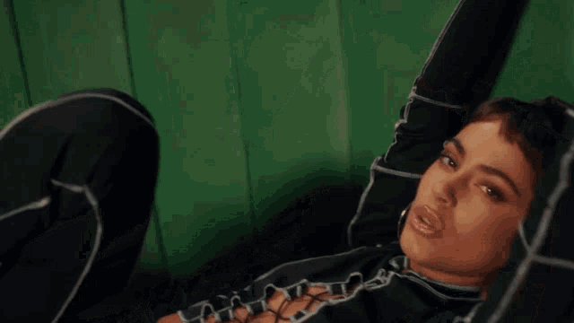 a woman with short hair is laying on a green couch with her hand on her head