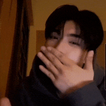 a man is covering his mouth with his hands while looking at the camera .