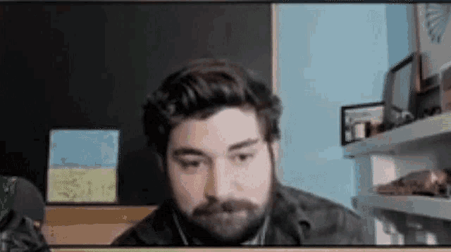 a man with a beard is sitting in front of a blackboard